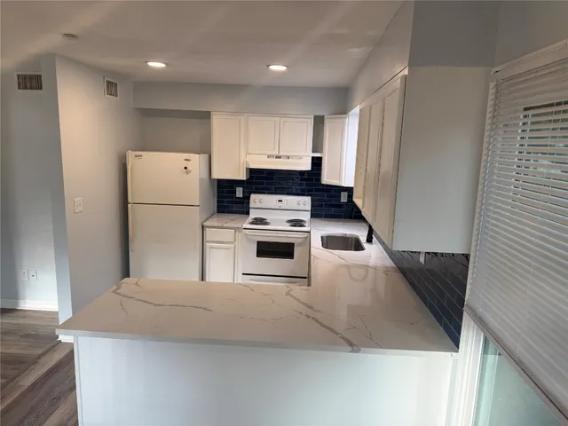 a kitchen with granite countertop a stove top oven and cabinets