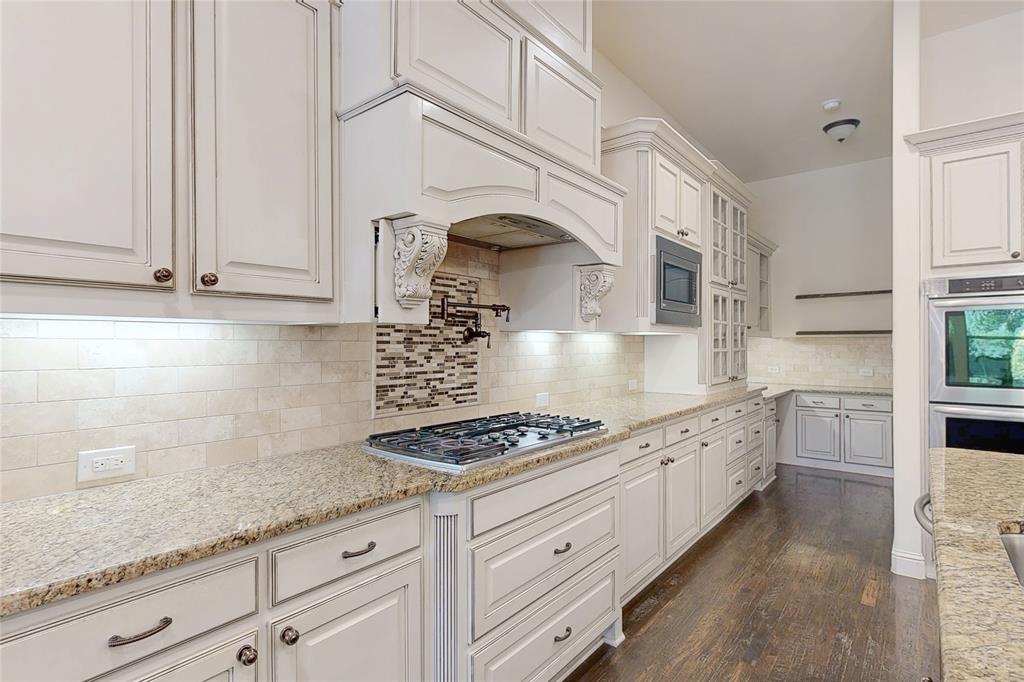 11048 Riney Court Frisco, TX 75035 - Photo 4 of 40 a kitchen with granite countertop a stove and white cabinets