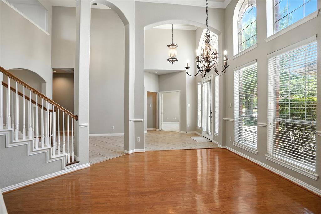 8220 Holliday Road Lantana, TX 76226 - Photo 12 of 40 Spacious entryway featuring high ceilings, archways, a grand staircase with wood railing, wood-finish flooring, and multiple large windows