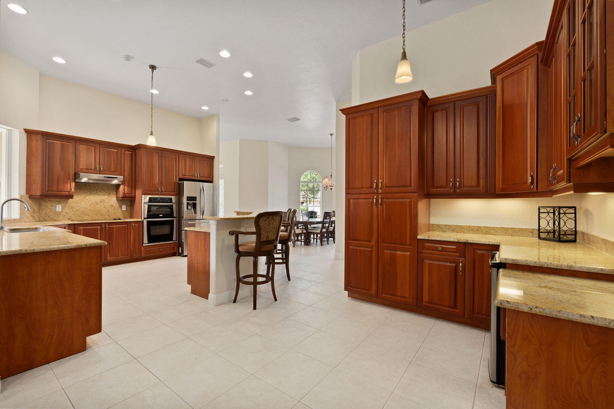 9523 Shadow Lane Fort Pierce, FL 34951 - Photo 14 of 32 a kitchen with stainless steel appliances kitchen island granite countertop a refrigerator oven a sink a dining table and chairs with wooden floor