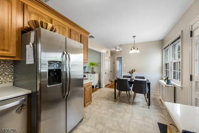 a kitchen with stainless steel appliances kitchen island granite countertop a refrigerator and a dining table