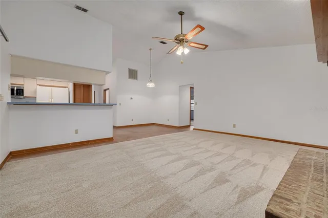 an empty room with a chandelier fan and windows