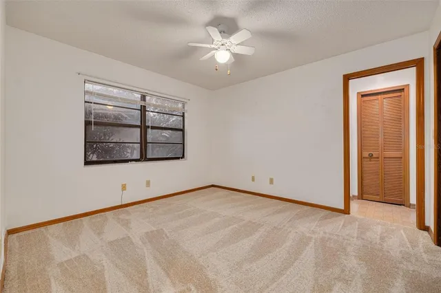 an empty room with windows and ceiling fan