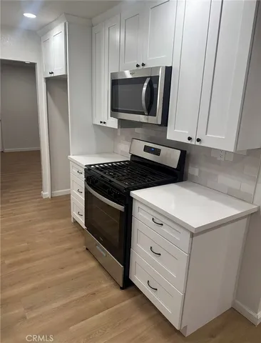 a kitchen with stainless steel appliances white cabinets and a stove top oven