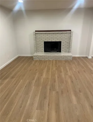 a view of empty room with wooden floor and fireplace