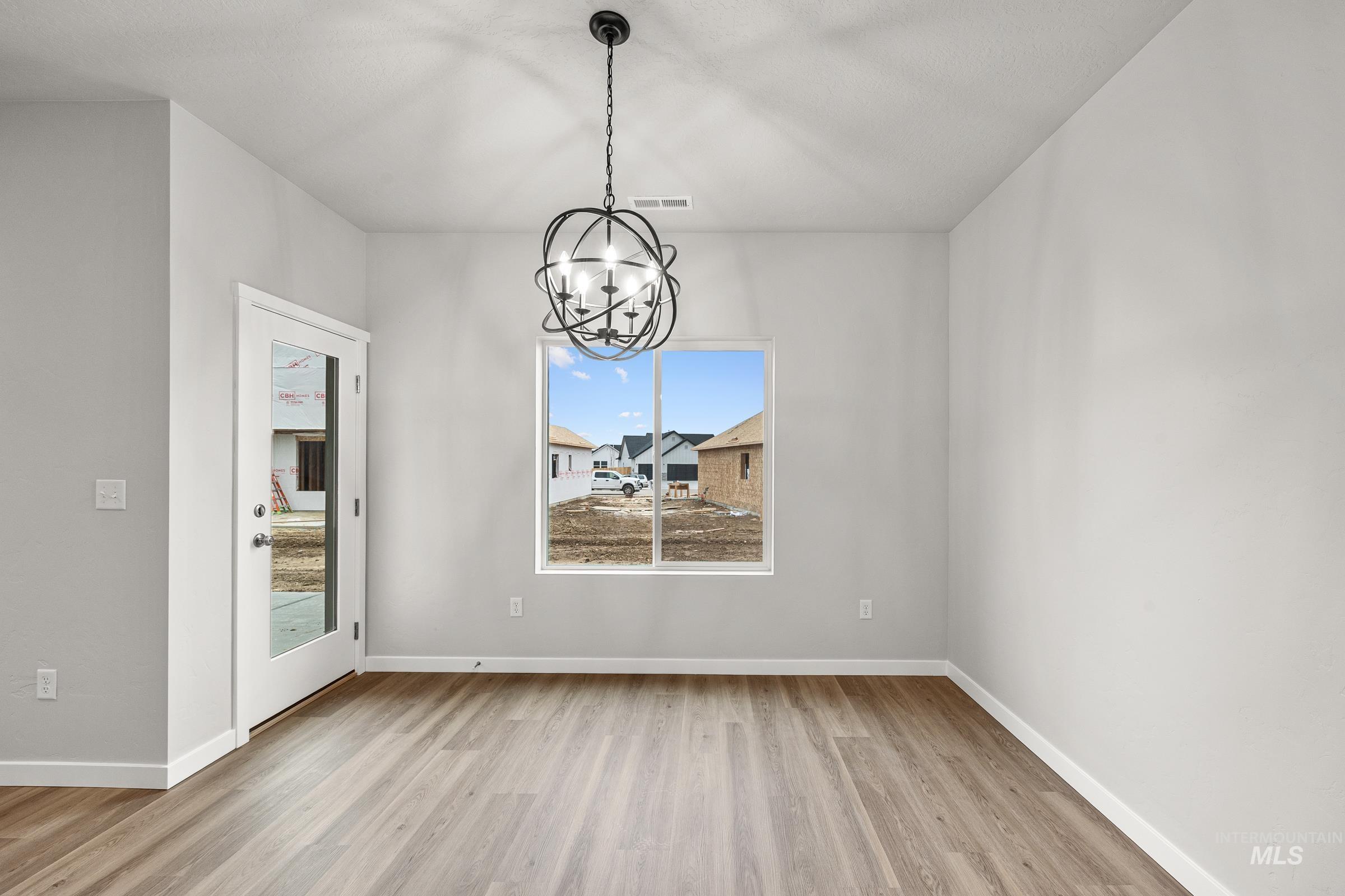 13656 Redway Court Caldwell, ID 83607 - Photo 7 of 21 Dining area featuring wood-finish flooring, a modern spherical chandelier, white baseboards, and two large windows with blinds