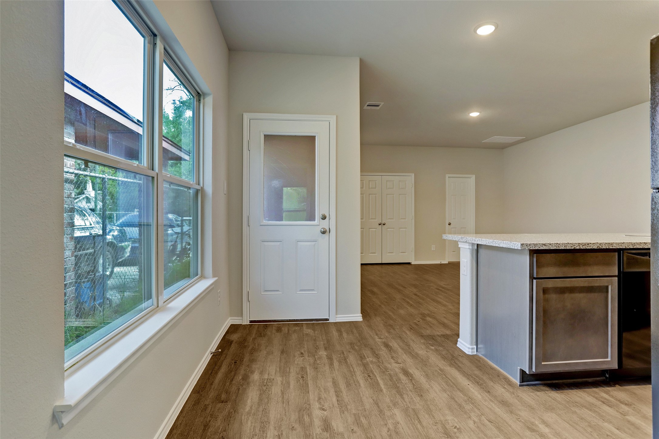 409 South 12th Street, Unit B Conroe, TX 77301 - Photo 7 of 14 Bright, open-concept interior with natural light from large windows. Features modern wood flooring, a neutral color palette, and a spacious kitchen with ample countertop space. Ideal for comfortable living and entertaining.