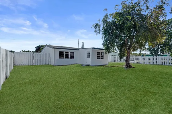 a view of a backyard with large trees and wooden fence