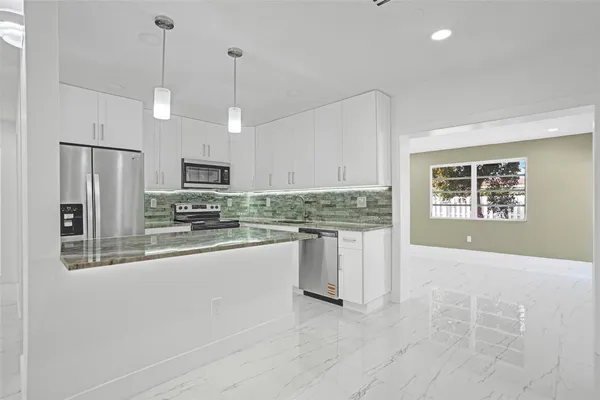 a kitchen with stainless steel appliances granite countertop a refrigerator a stove a sink and white cabinets
