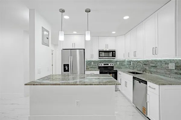a kitchen with stainless steel appliances kitchen island granite countertop a refrigerator a sink and a stove