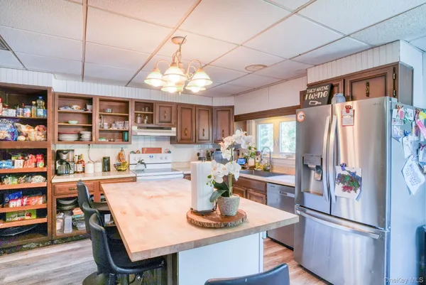 a kitchen with stainless steel appliances granite countertop a refrigerator a sink dishwasher a dining table and chairs with wooden floor