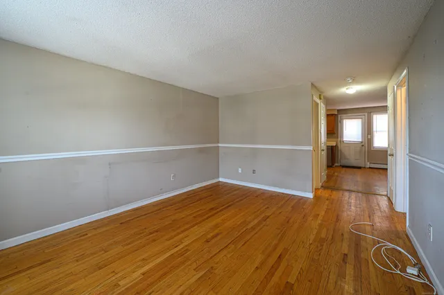 a view of an empty room with wooden floor and stairs