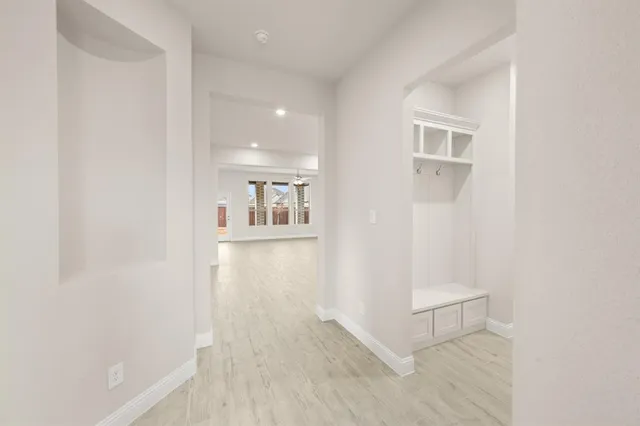 a view of a hallway with wooden floor and a bathroom