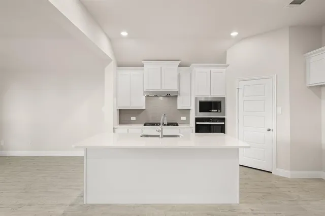 a kitchen with stainless steel appliances a sink a stove a microwave a sink a refrigerator and cabinets