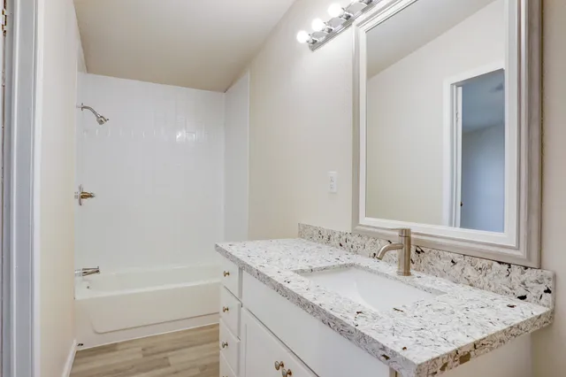 a bathroom with a granite countertop sink and a bathtub