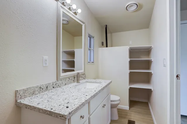 a bathroom with a granite countertop sink and a toilet