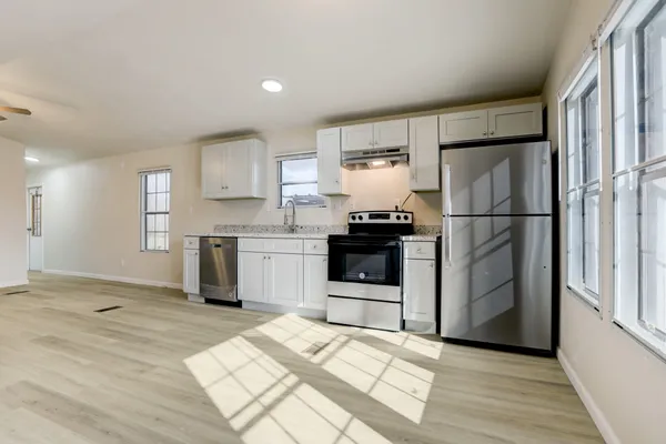 a kitchen with granite countertop a refrigerator sink and cabinets