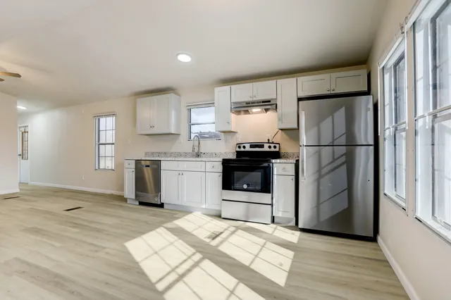 a kitchen with granite countertop a refrigerator sink and cabinets