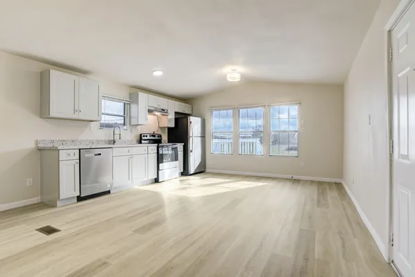 a kitchen with stainless steel appliances granite countertop a stove top oven a sink dishwasher and a refrigerator with wooden floor