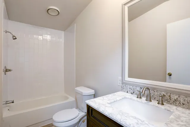 a bathroom with a granite countertop sink toilet and shower