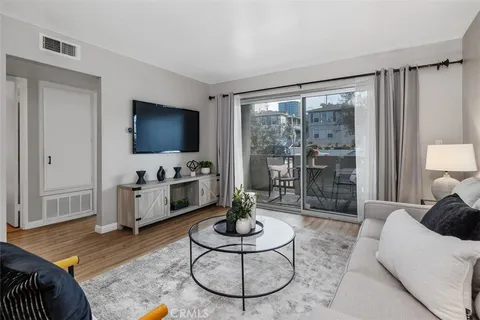 a living room with furniture a flat screen tv and a floor to ceiling window