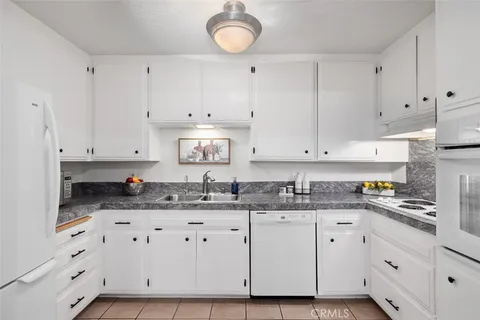a kitchen with granite countertop a sink cabinets and stainless steel appliances