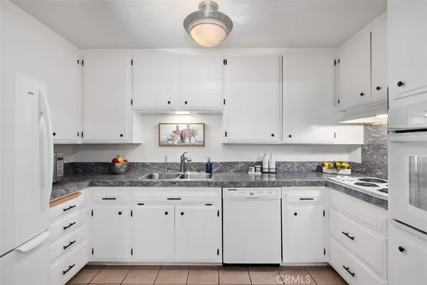 a kitchen with granite countertop a sink cabinets and stainless steel appliances