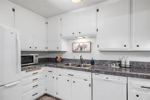 a kitchen with granite countertop white cabinets sink and stainless steel appliances