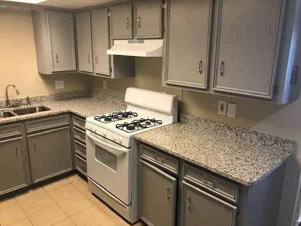 a kitchen with granite countertop a sink stove and cabinets