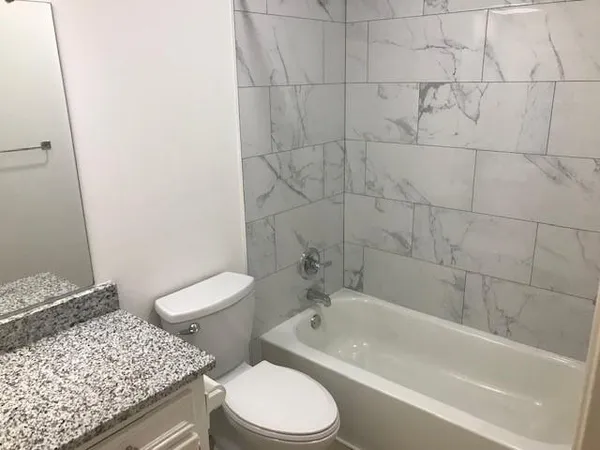 a bathroom with a granite countertop toilet a sink and bathtub