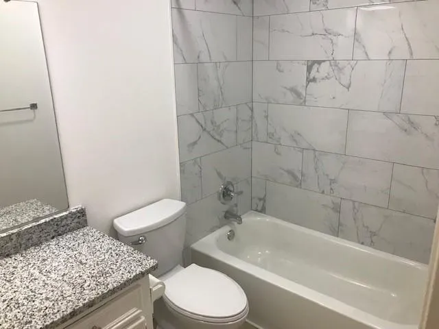 a bathroom with a granite countertop toilet a sink and bathtub