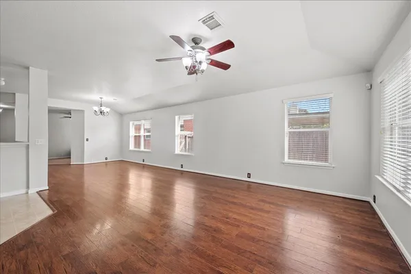 a view of empty room with wooden floor and a ceiling fan