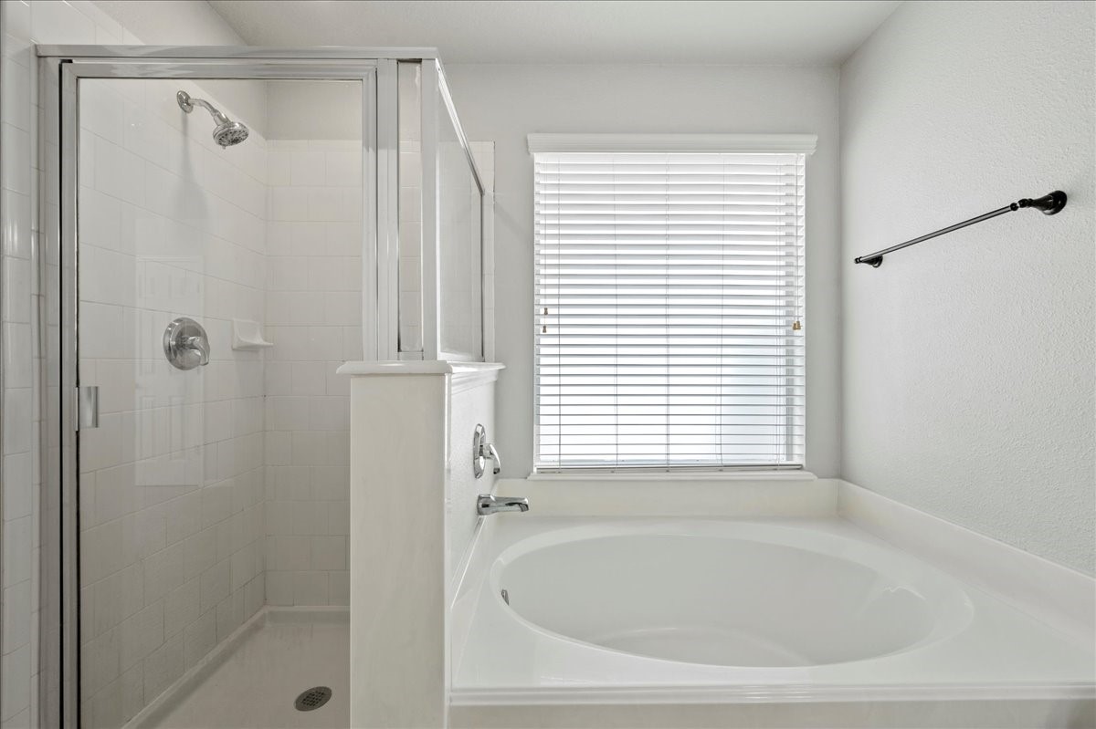 17535 Prospect Meadows Drive Houston, TX 77095 - Photo 21 of 39 While a large soaking tub invites relaxation, a separate glass-enclosed shower features sleek tile work, and natural light filters in through frosted windows, creating a serene bathing experience.