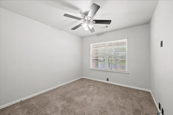 an empty room with a window and a ceiling fan