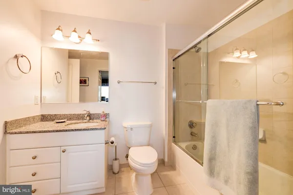 a bathroom with a toilet sink vanity granite and shower