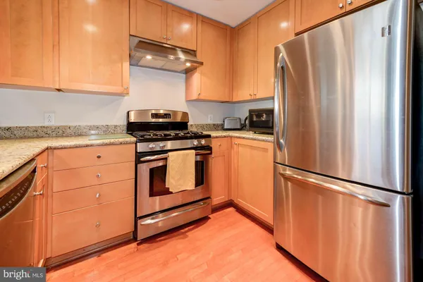 a kitchen with granite countertop a refrigerator stove and cabinets