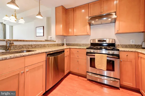 a kitchen with stainless steel appliances granite countertop a stove a sink and a microwave