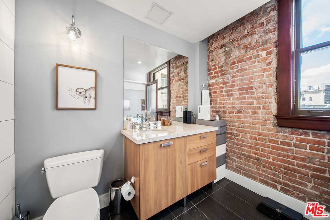 460 South Spring Street, Unit 1205 Los Angeles, CA 90013 - Photo 19 of 37 a bathroom with a toilet a sink and a large mirror