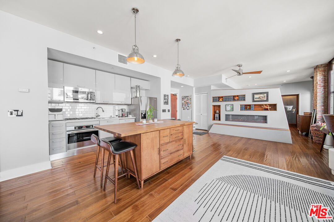 460 South Spring Street, Unit 1205 Los Angeles, CA 90013 - Photo 4 of 37 a open kitchen with stainless steel appliances granite countertop a stove a sink dishwasher and a dining table with wooden floor
