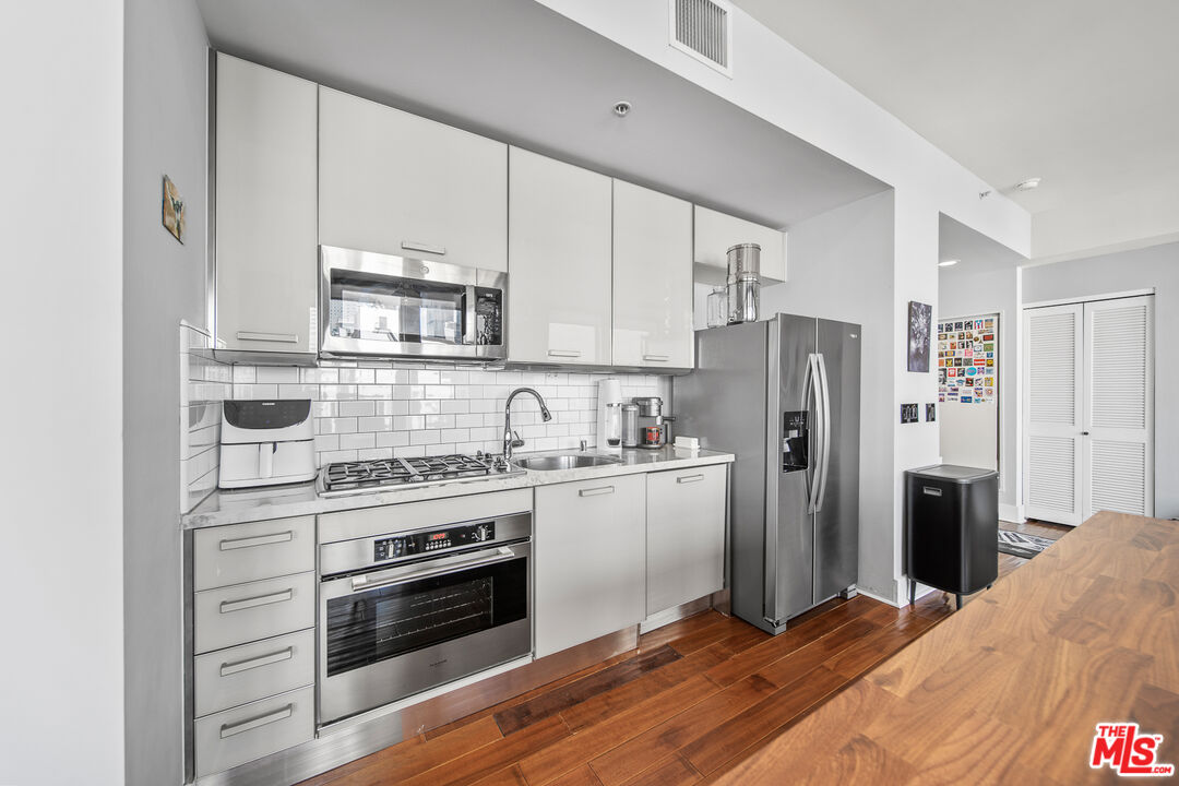 460 South Spring Street, Unit 1205 Los Angeles, CA 90013 - Photo 10 of 37 a kitchen with stainless steel appliances a stove a refrigerator and a sink
