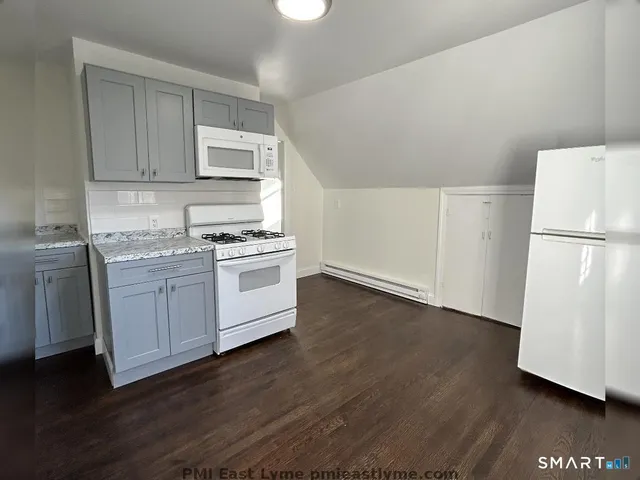 a kitchen with a white refrigerator a sink a stove a microwave and cabinets