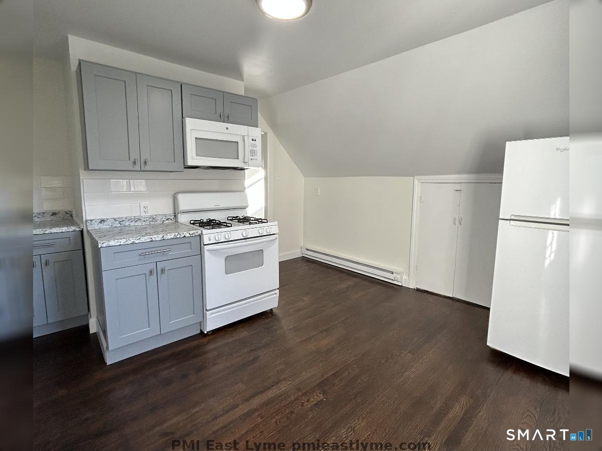 54 Roath Street Norwich, CT 06360 - Photo 13 of 16 a kitchen with a white refrigerator a sink a stove a microwave and cabinets