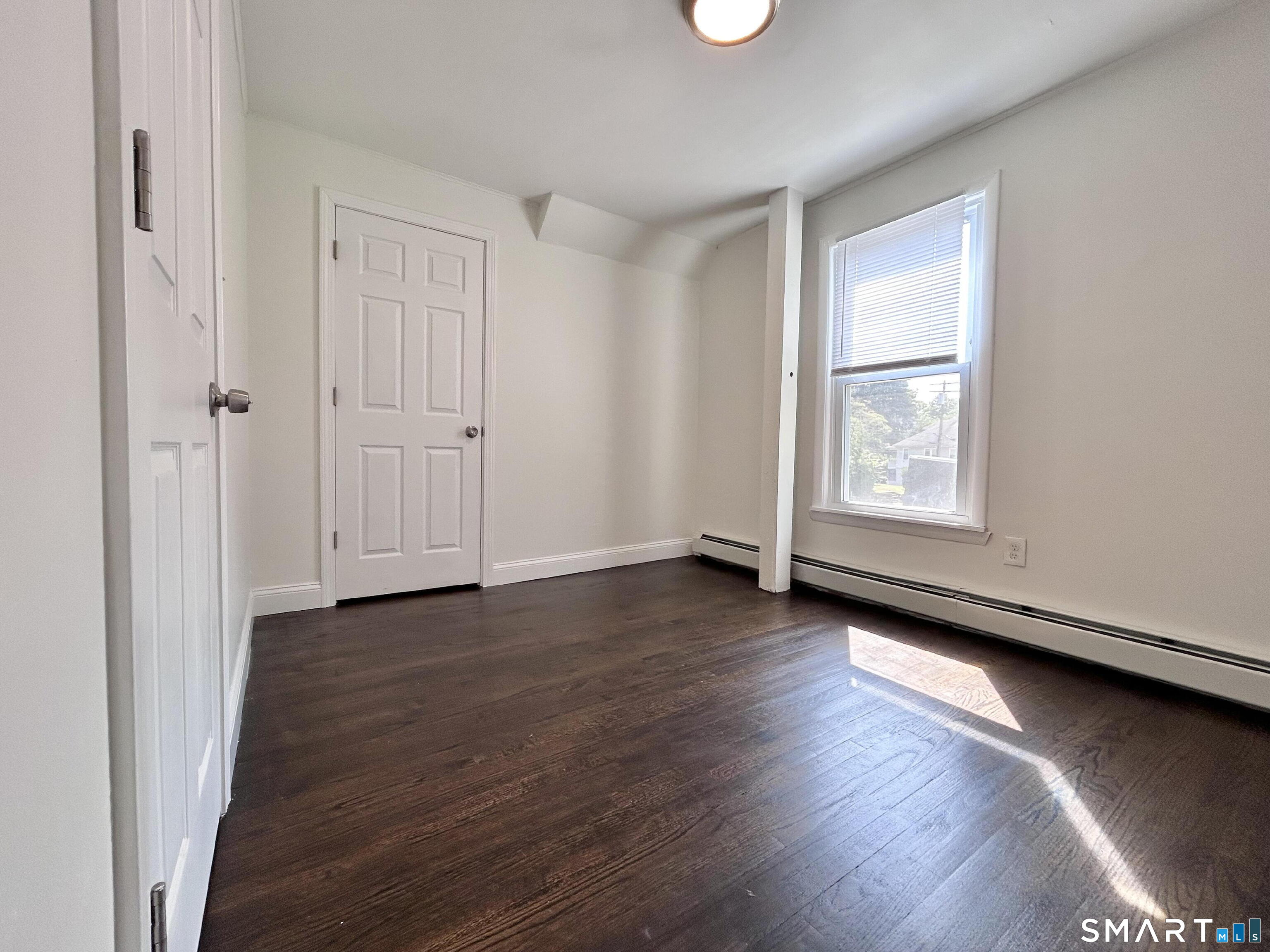 54 Roath Street Norwich, CT 06360 - Photo 8 of 16 an empty room with wooden floor and windows