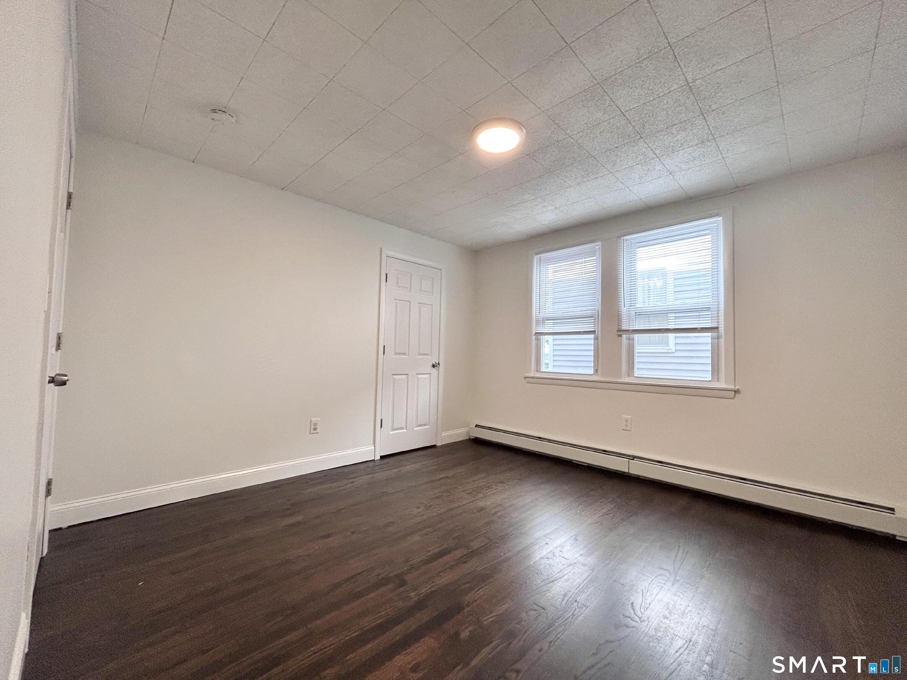 54 Roath Street Norwich, CT 06360 - Photo 10 of 16 an empty room with wooden floor and windows