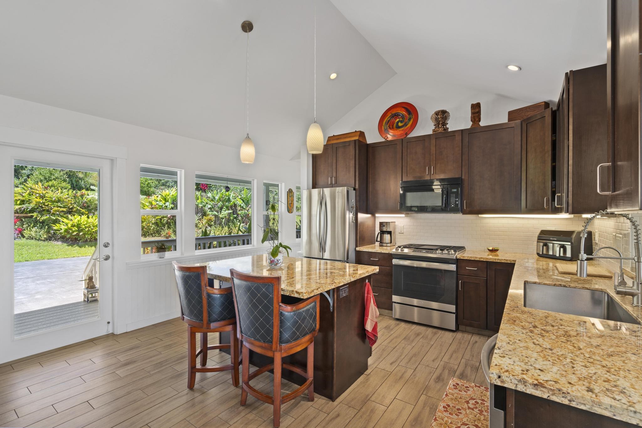 896 Hoomalolo Place, Unit B Haiku, HI 96708 - Photo 16 of 44 a kitchen with stainless steel appliances granite countertop a stove top oven a sink dishwasher and a dining table with wooden floor
