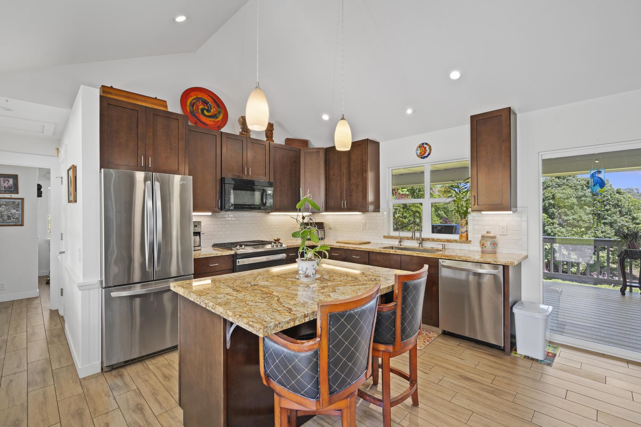 896 Hoomalolo Place, Unit B Haiku, HI 96708 - Photo 17 of 44 a kitchen with a refrigerator a stove a sink and a dining table with wooden floor