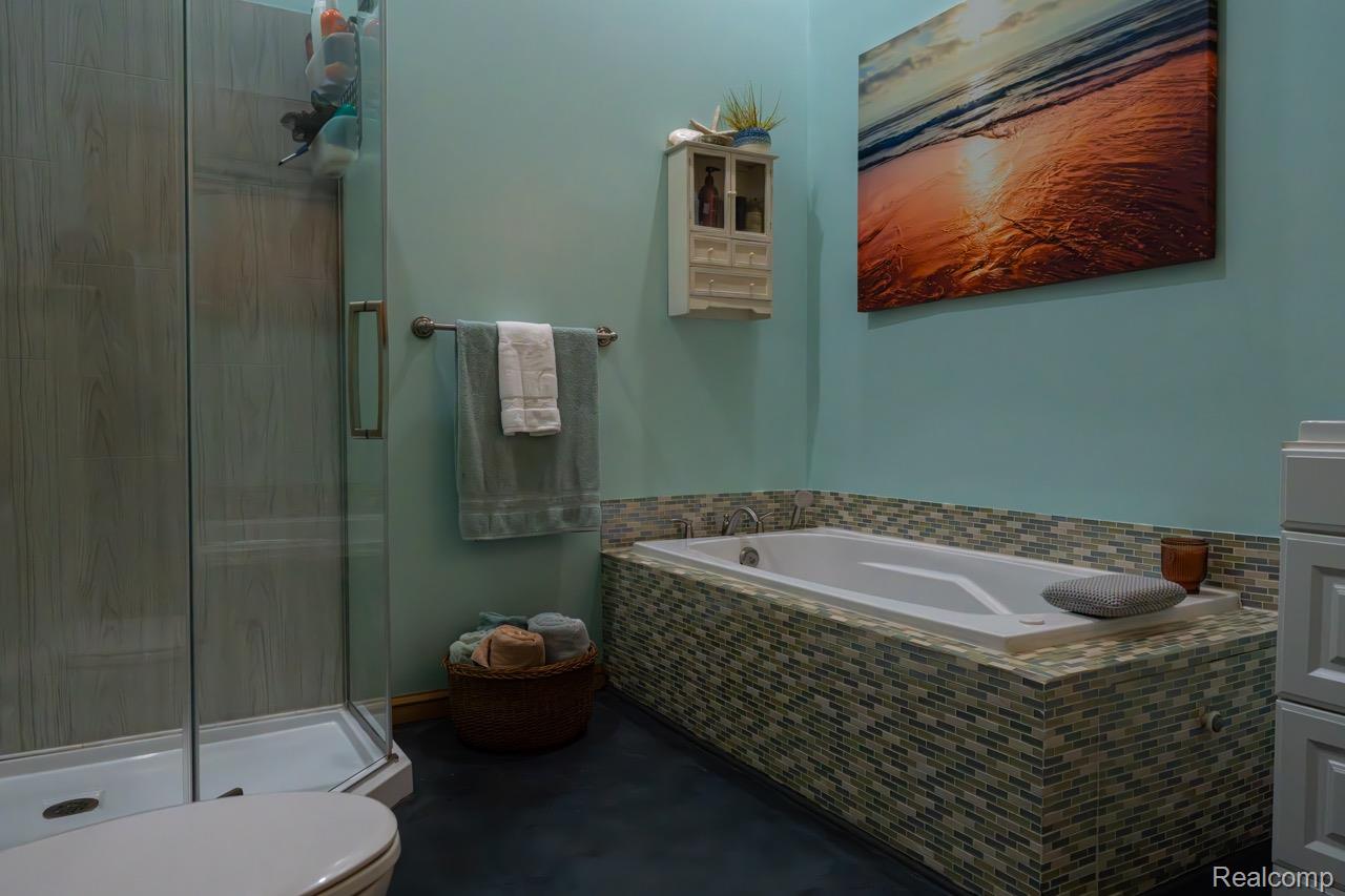2418 South 41st Road South Cadillac, MI 49601 - Photo 20 of 57 Built-in soaking tub with mosaic tile surround, featuring a wall-mounted faucet