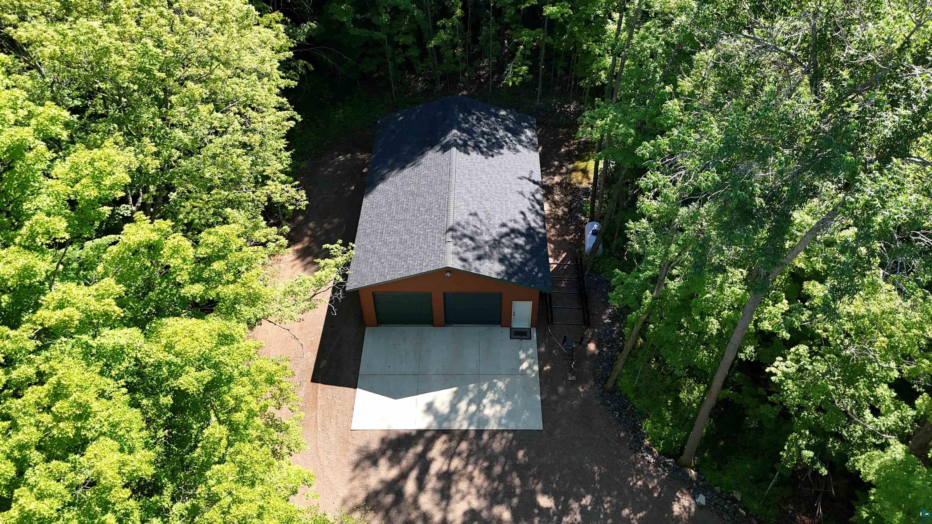 4613 North Lake Winter Road Winter, WI 54896 - Photo 66 of 73 Detached garage with dual garage doors, a concrete driveway, and a shingle roof, surrounded by mature trees