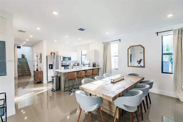 a dining room with kitchen island stainless steel appliances furniture a dining table and kitchen view