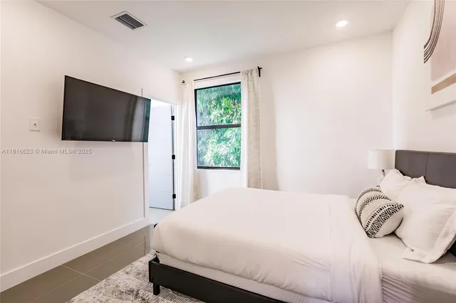 a bedroom with a bed tv and a window